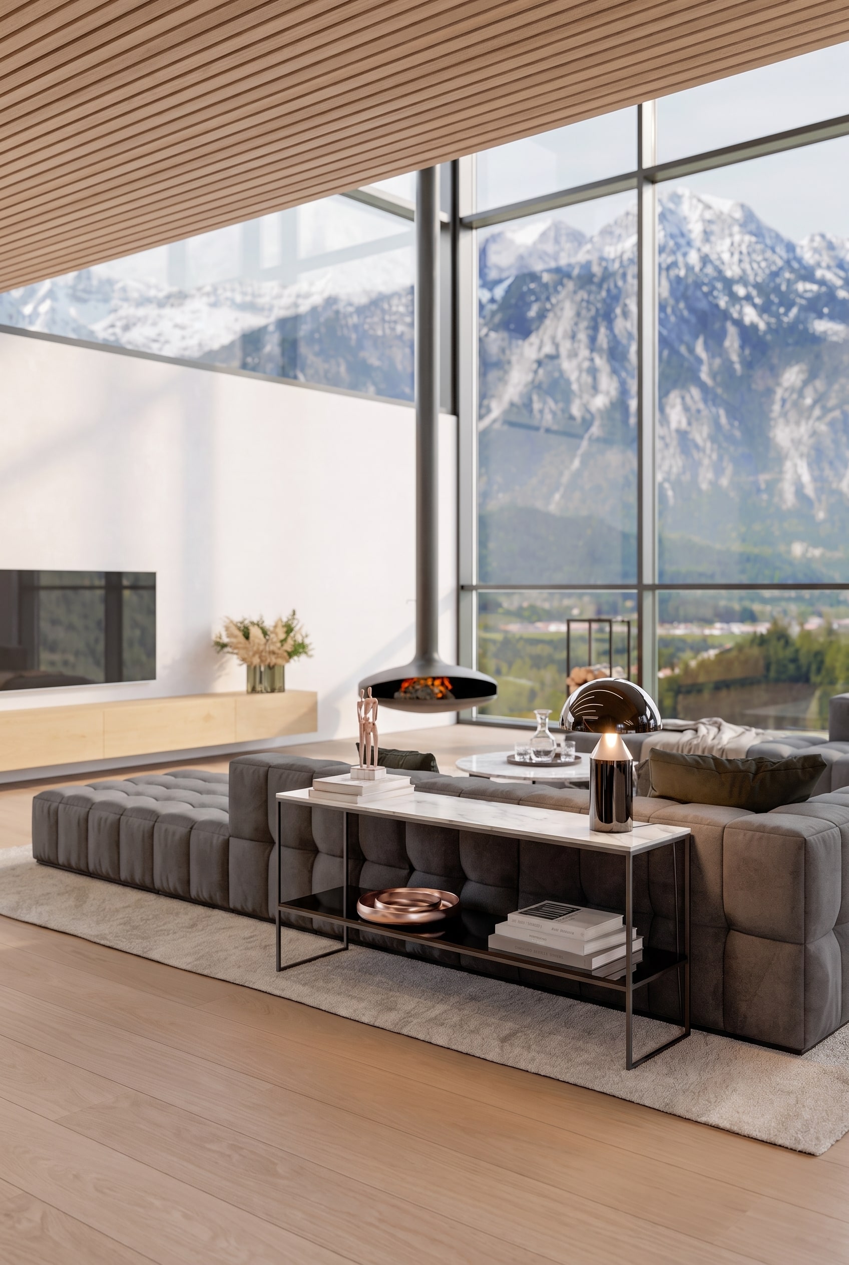 Rückansicht eines grauen Sofas im Wohnzimmer, dahinter eine schmale, minimalistische Metallkonsole mit Marmorplatte, bestückt mit Tischleuchte und Büchern.