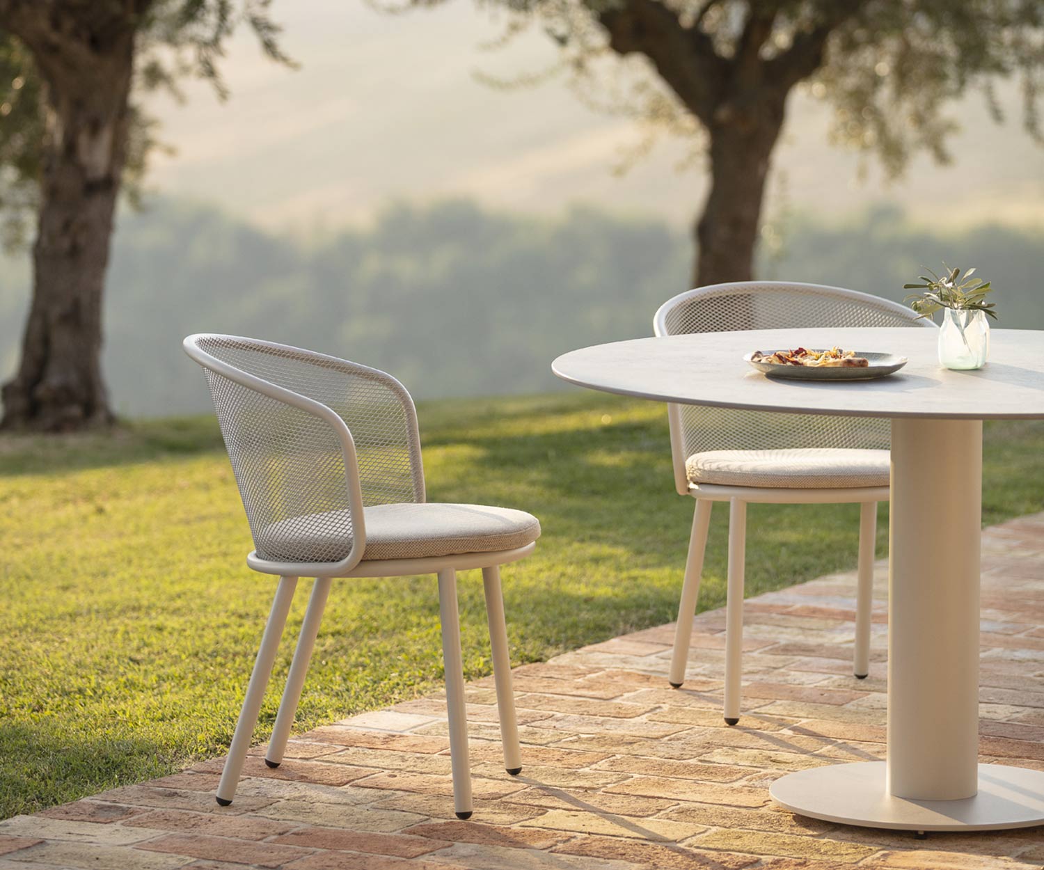 Chaise à accoudoirs design blanche Todus Baza avec revêtement en tissu gris dans le jardin