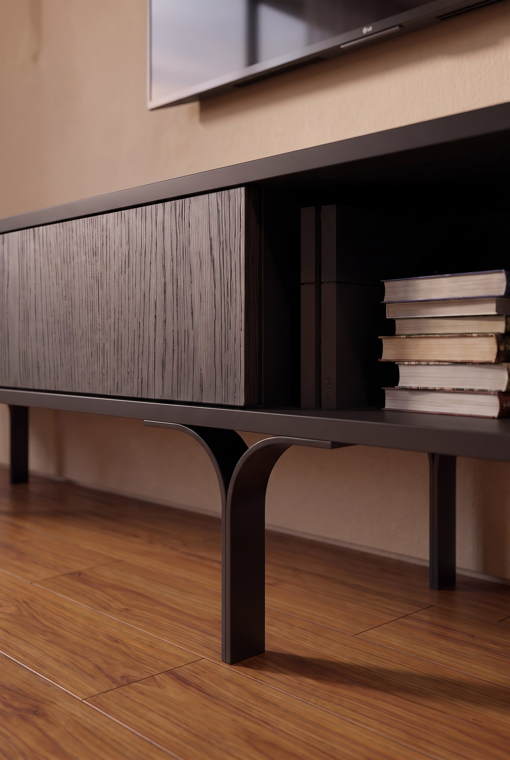 Detailaufnahme eines dunklen Lowboards mit strukturierter Holz-Schiebet&uuml;r, B&uuml;chern und filigran gebogenen Metallf&uuml;&szlig;en.