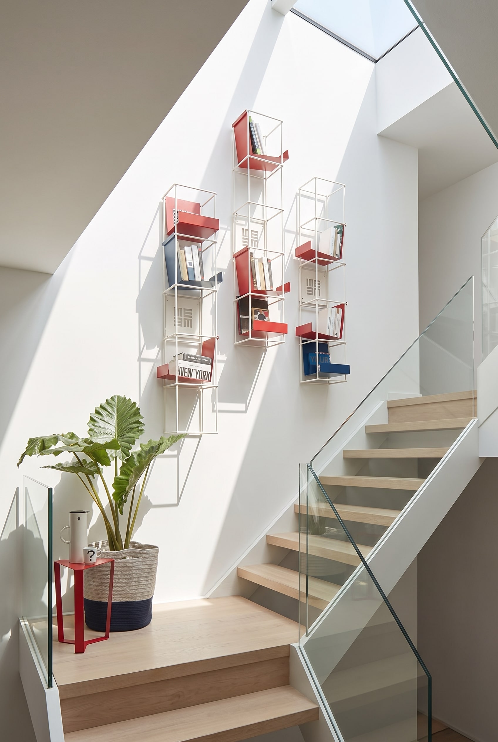&Eacute;tag&egrave;re murale modulaire ouverte Livitalia Tetris sur le mur blanc d'une cage d'escalier moderne, remplie de livres et de d&eacute;coration