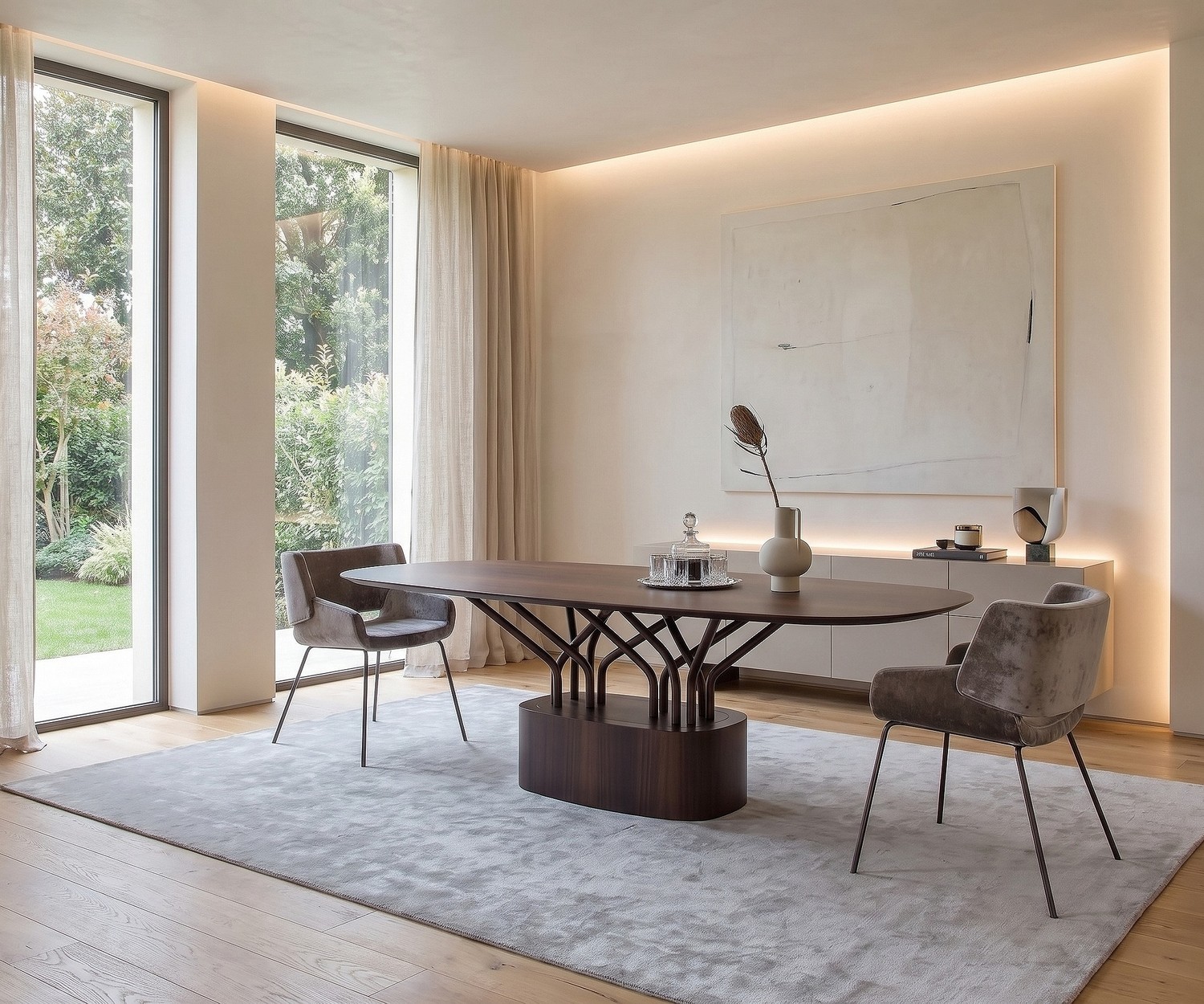 al2 wood-oo Design Esstisch oval Ovaler al2 wood-oo Esstisch aus Holz im modernen Esszimmer mit zwei grauen Samtsesseln vor großen Fenstern.