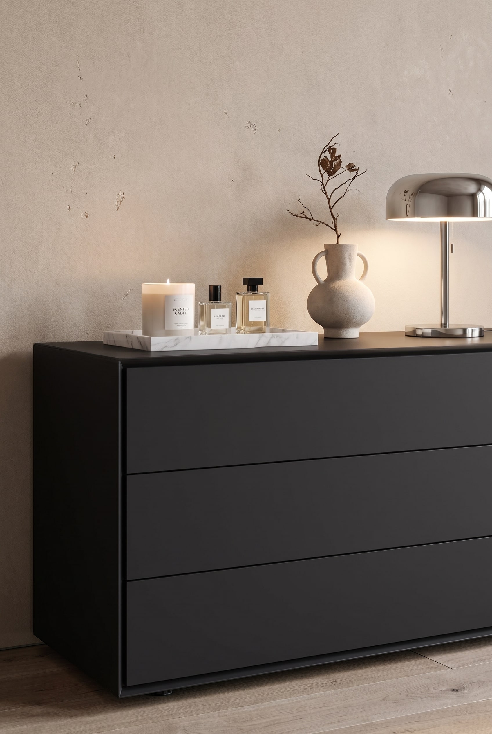 Commode design mate dans l'espace salon-chambre, avec des livres d'art empil&eacute;s, un vase sculptural et une petite lampe de table