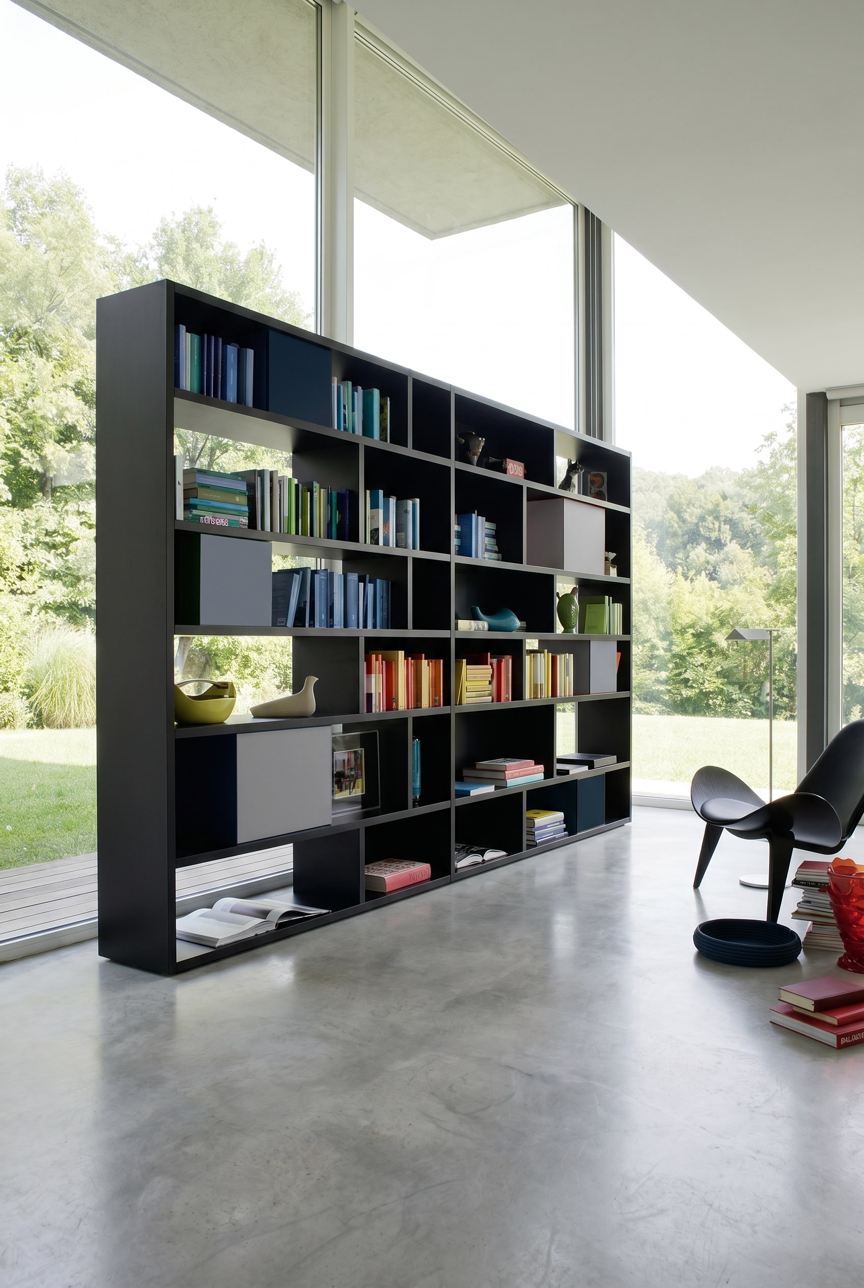 Mattschwarzes asymmetrisches Design-Regal mit integrierten grauen und blauen Aufbewahrungsboxen vor weißen Wänden