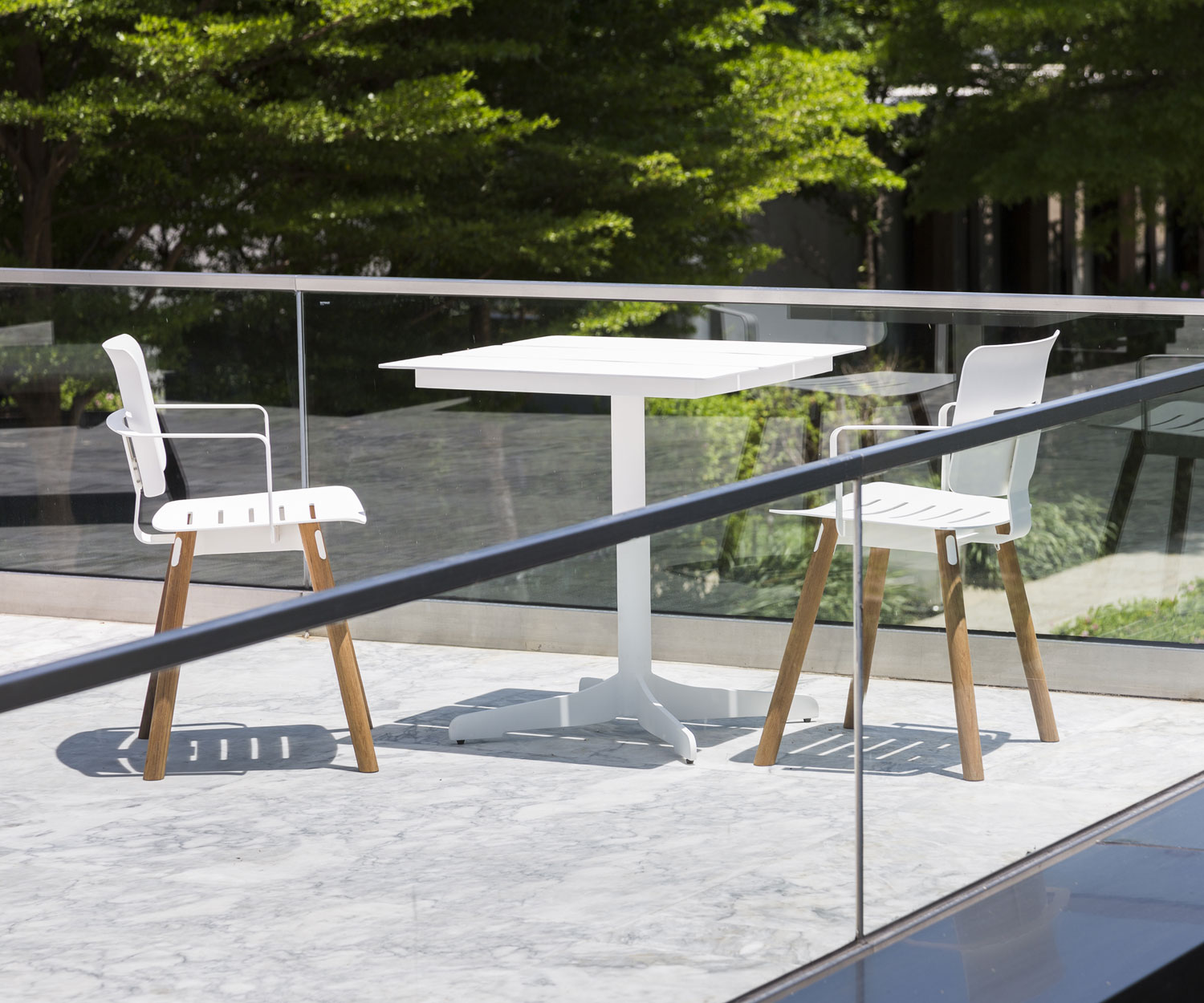 Table de jardin blanche Oasiq Ceru Design avec deux chaises de jardin sur terrasse
