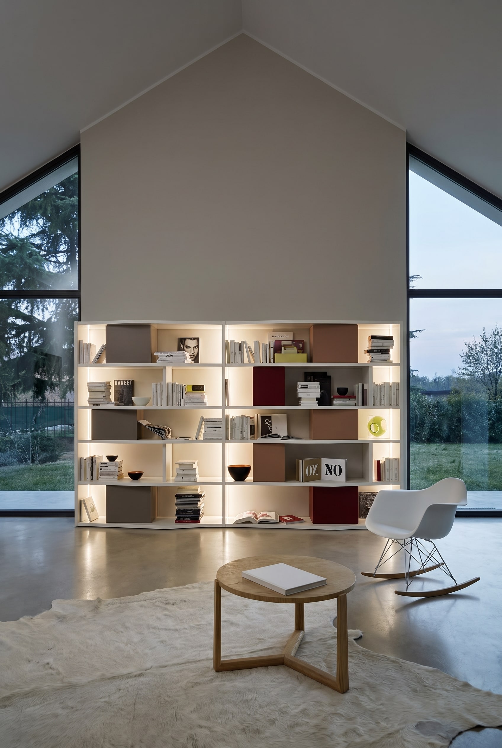 Haute bibliothèque blanche sur un mur pignon droit dans les combles, garnie de livres et de boîtes de rangement colorées