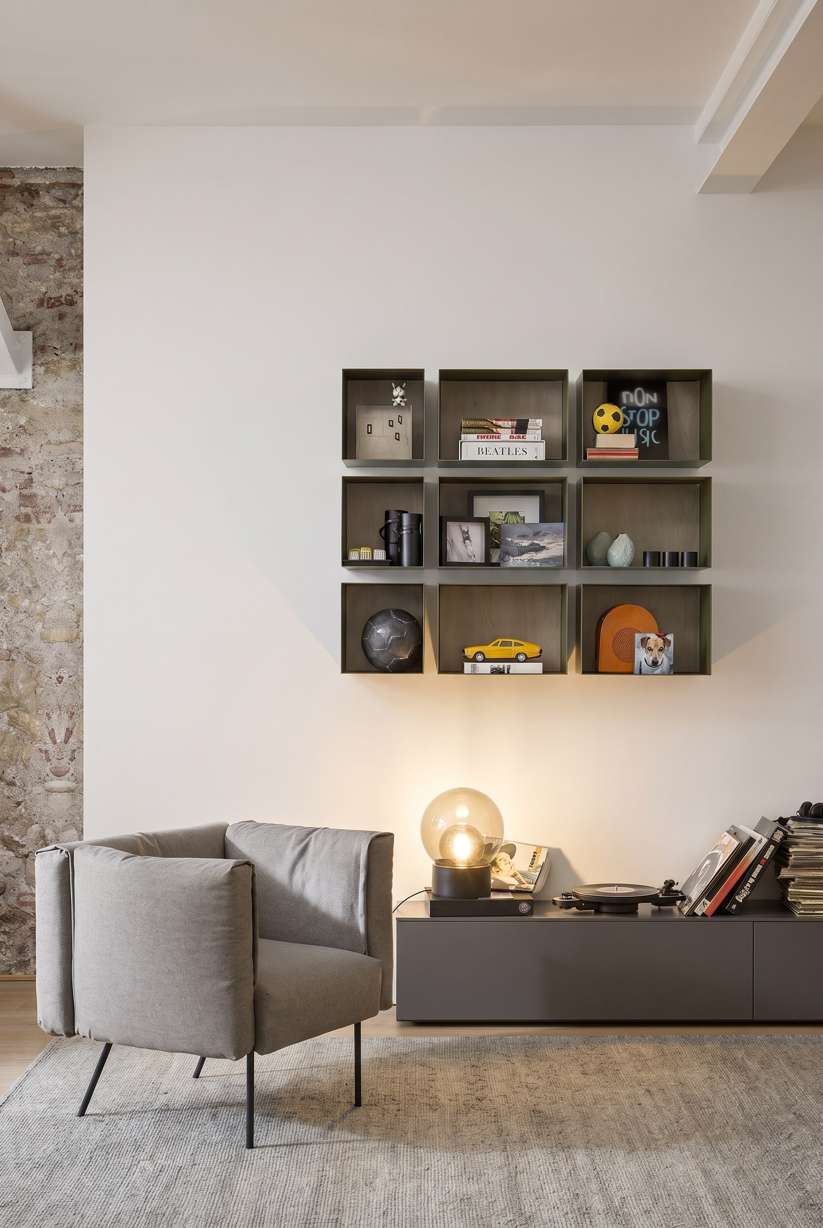 Minimalistische Leseecke mit schwebenden schwarzen Metall-Wandboxen, die mit Büchern gefüllt sind, und einem organisch geformten Sessel.