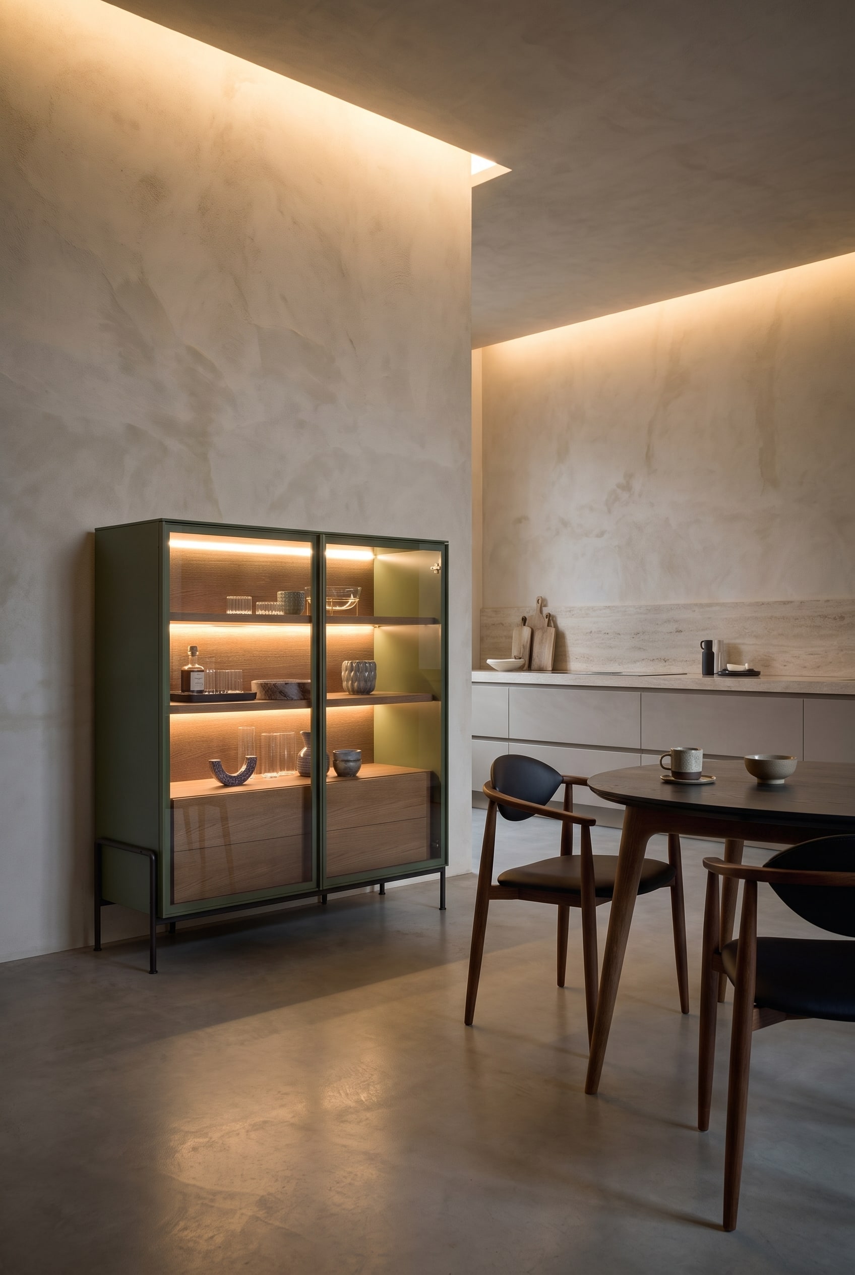Cuisine ouverte élégante avec un highboard haut aux bords arrondis, à côté d'une table à manger minimaliste avec des chaises