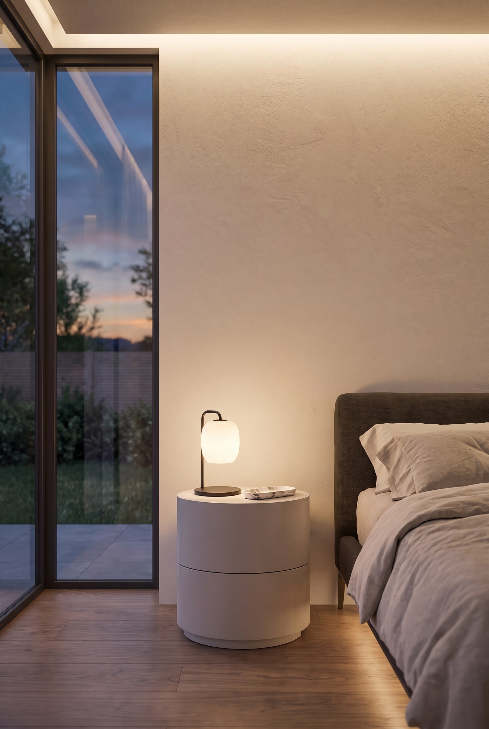 Table de chevet cylindrique et mate avec deux tiroirs, plac&eacute;e directement &agrave; c&ocirc;t&eacute; d'un lit rembourr&eacute; moderne.