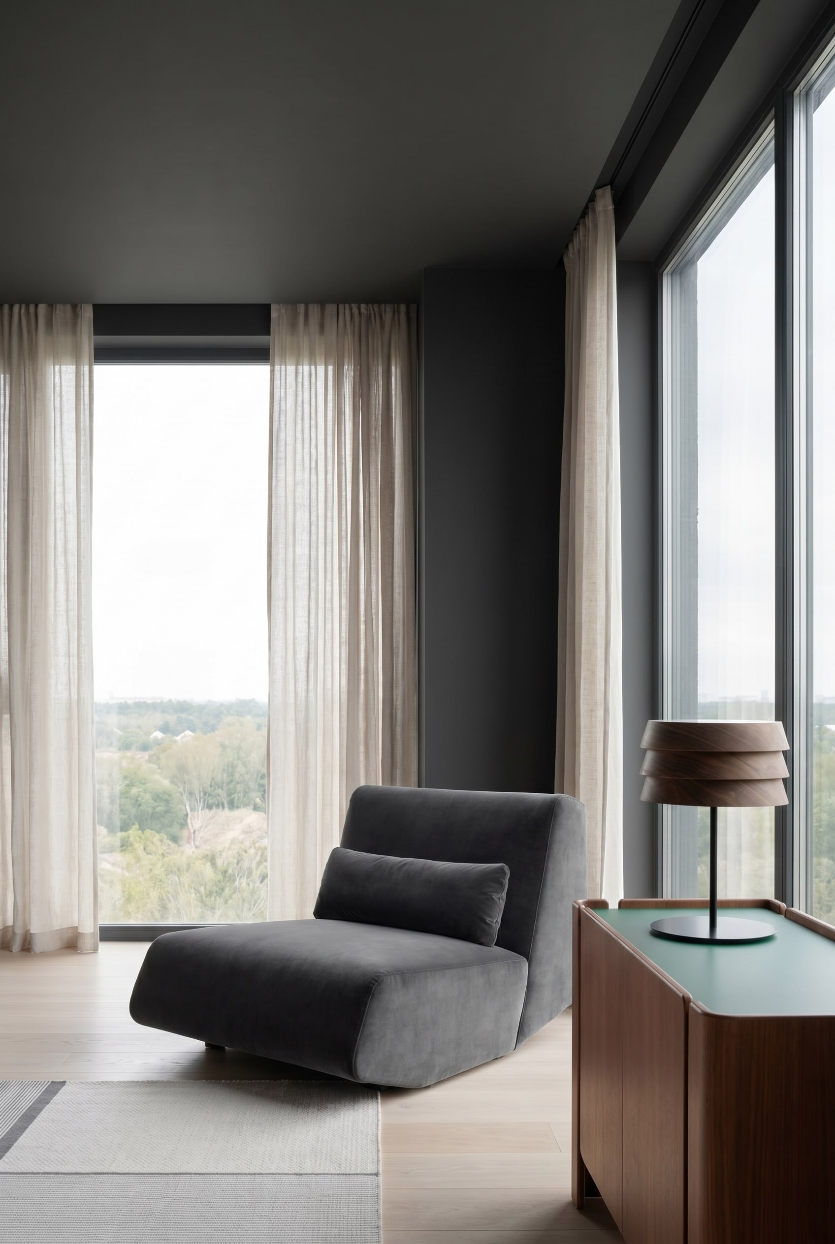 Modernes Wohnzimmer mit samtigem tiefen Lounge Sessel in Dunkelgrau und nahtlos dunkel gestrichenen Wänden