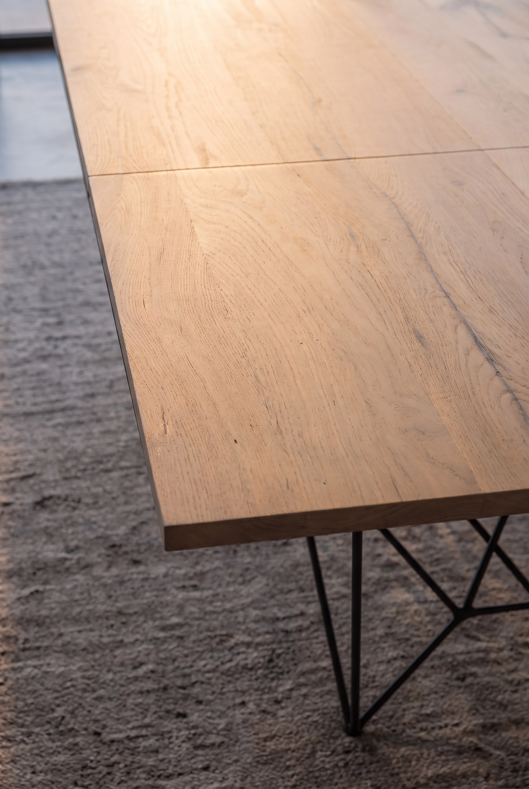 Vue détaillée du bord en bois et du piètement en métal noir de la table à manger Ozzio Fil8.