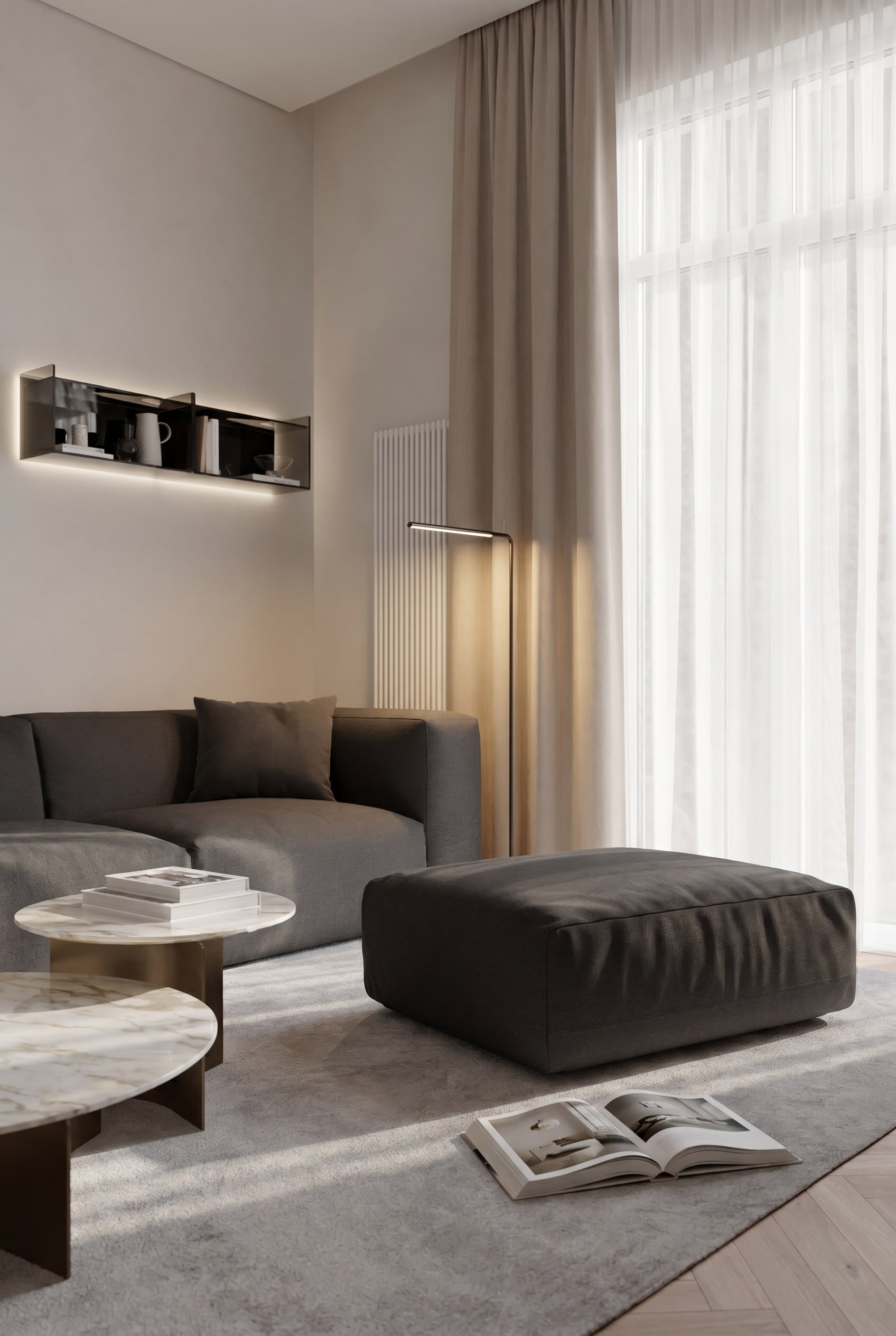Elegante Leseecke mit Pouf Cloud in dunklem Stoffbezug, passendem Relaxsessel und einer schlanken Stehleuchte