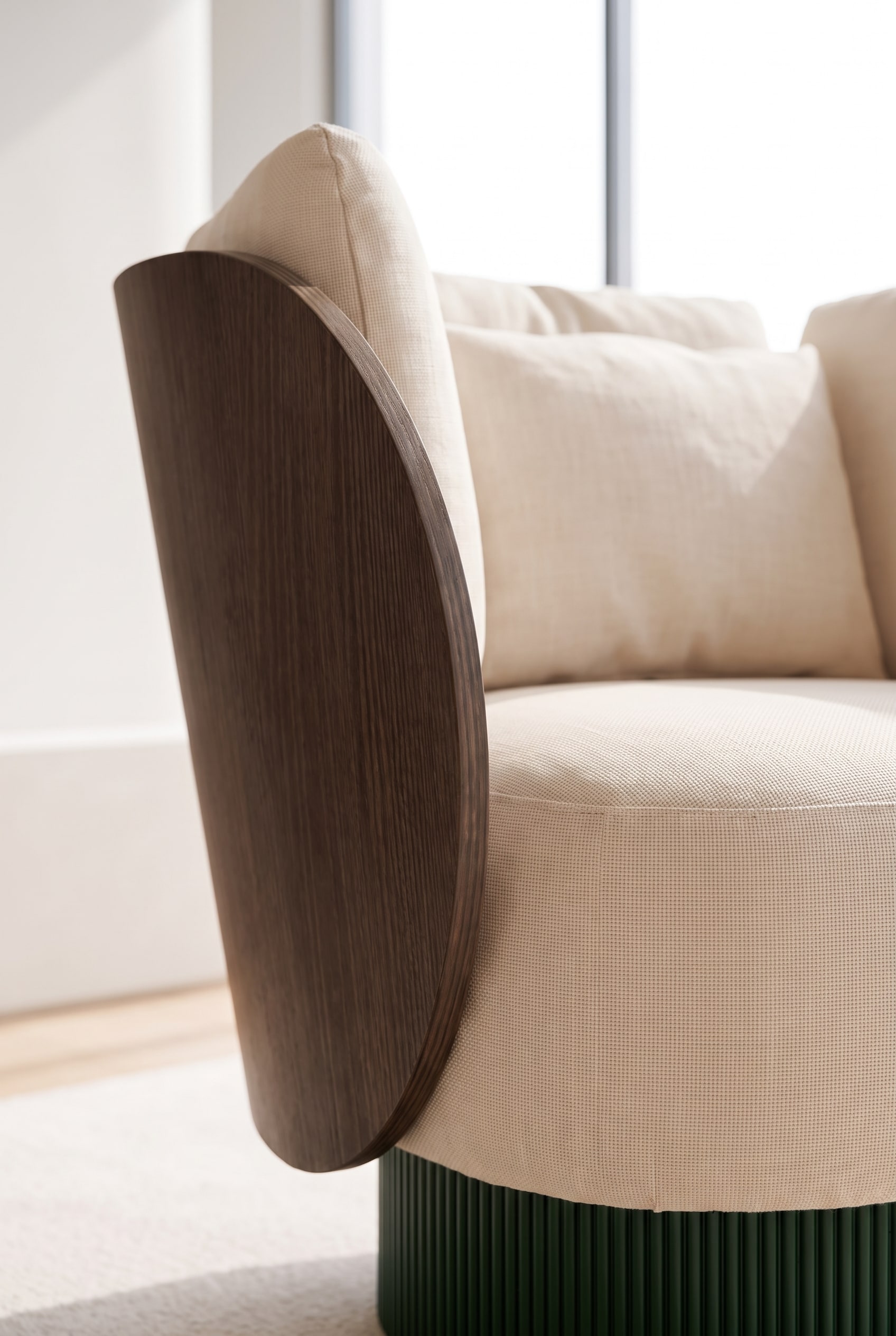 Gros plan de la combinaison de matériaux : bois courbé, socle rainuré et tissu premium beige.