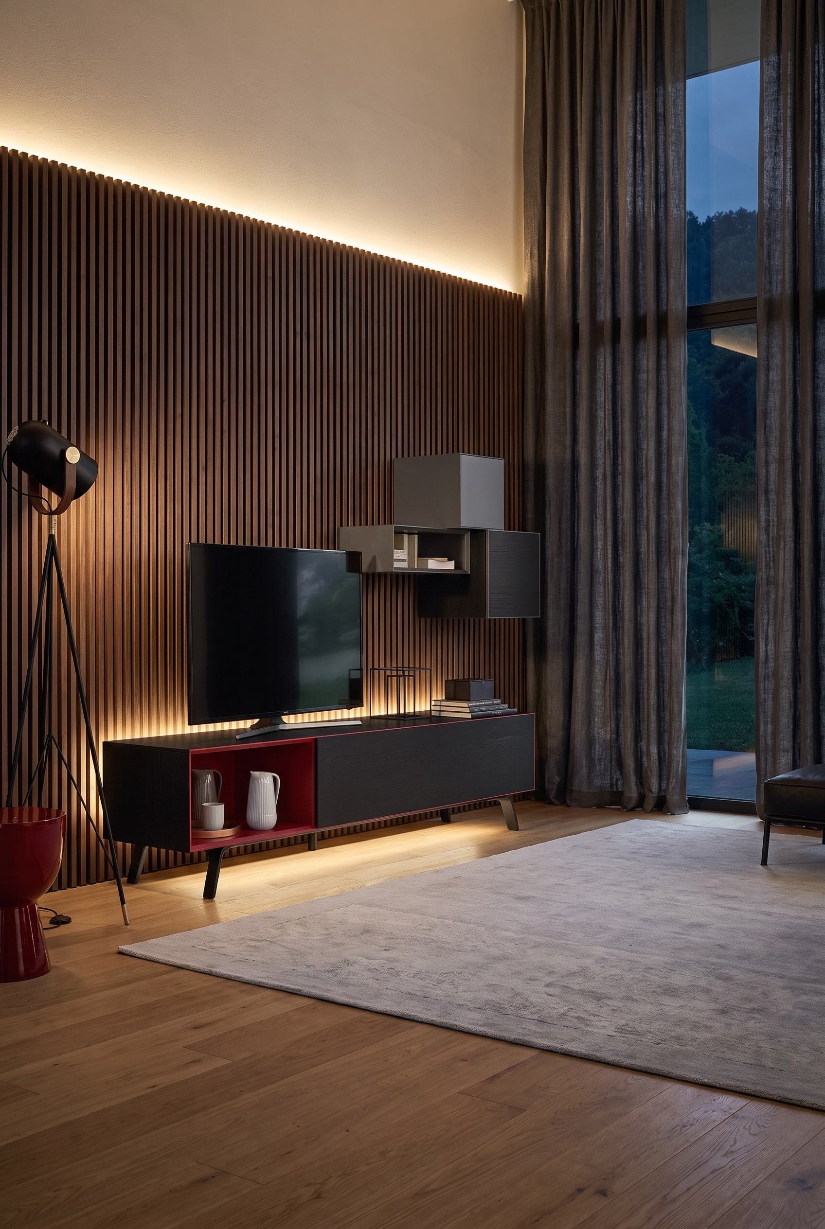 Grand salon le soir avec un meuble bas marron foncé, un panneau TV pivotant, un mur à lattes éclairé en arrière-plan et de lourds rideaux aux fenêtres