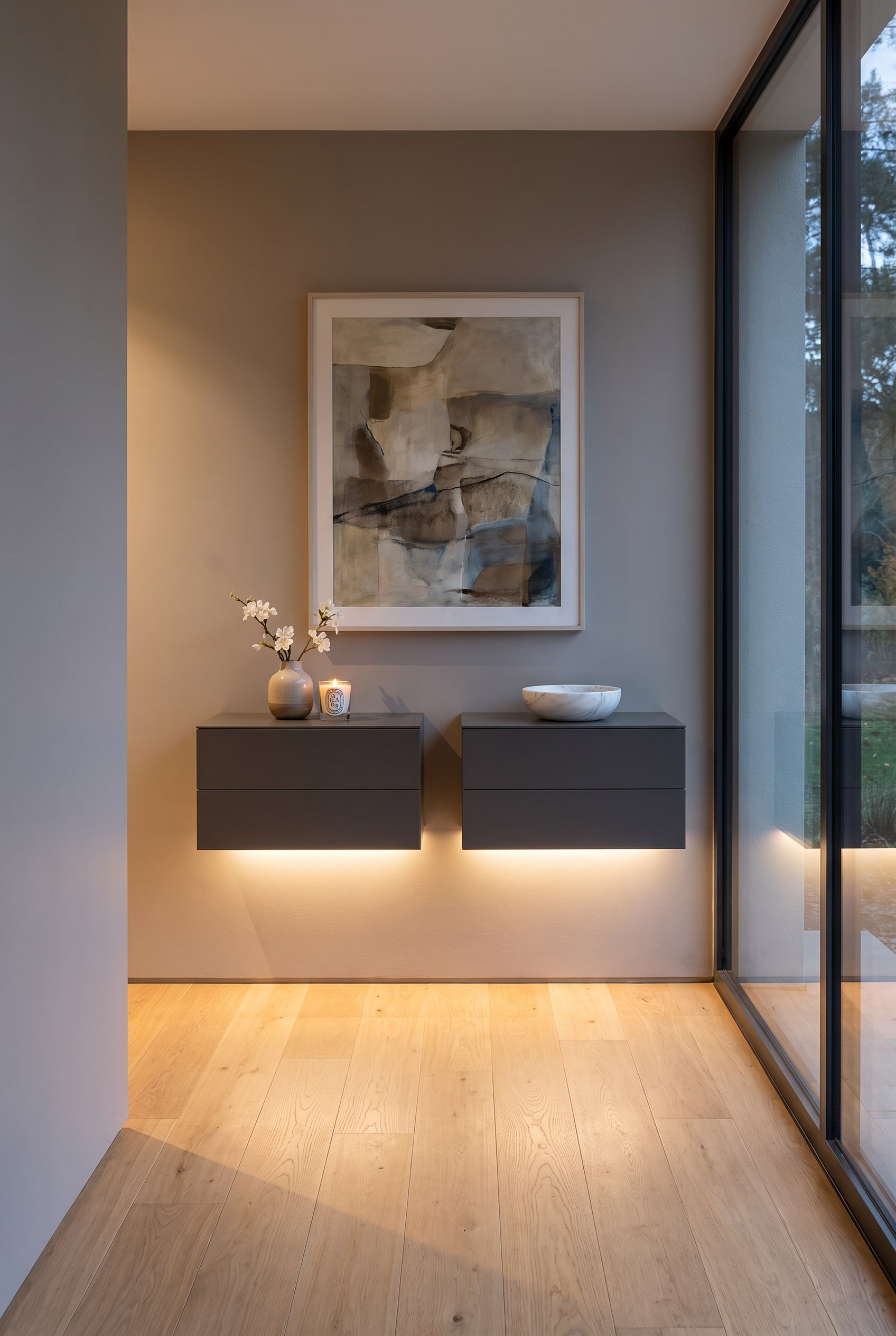 Une commode suspendue moderne et sans poignée à deux tiroirs sur le mur d'un couloir étroit, sous la commode brille un éclairage indirect doux.
