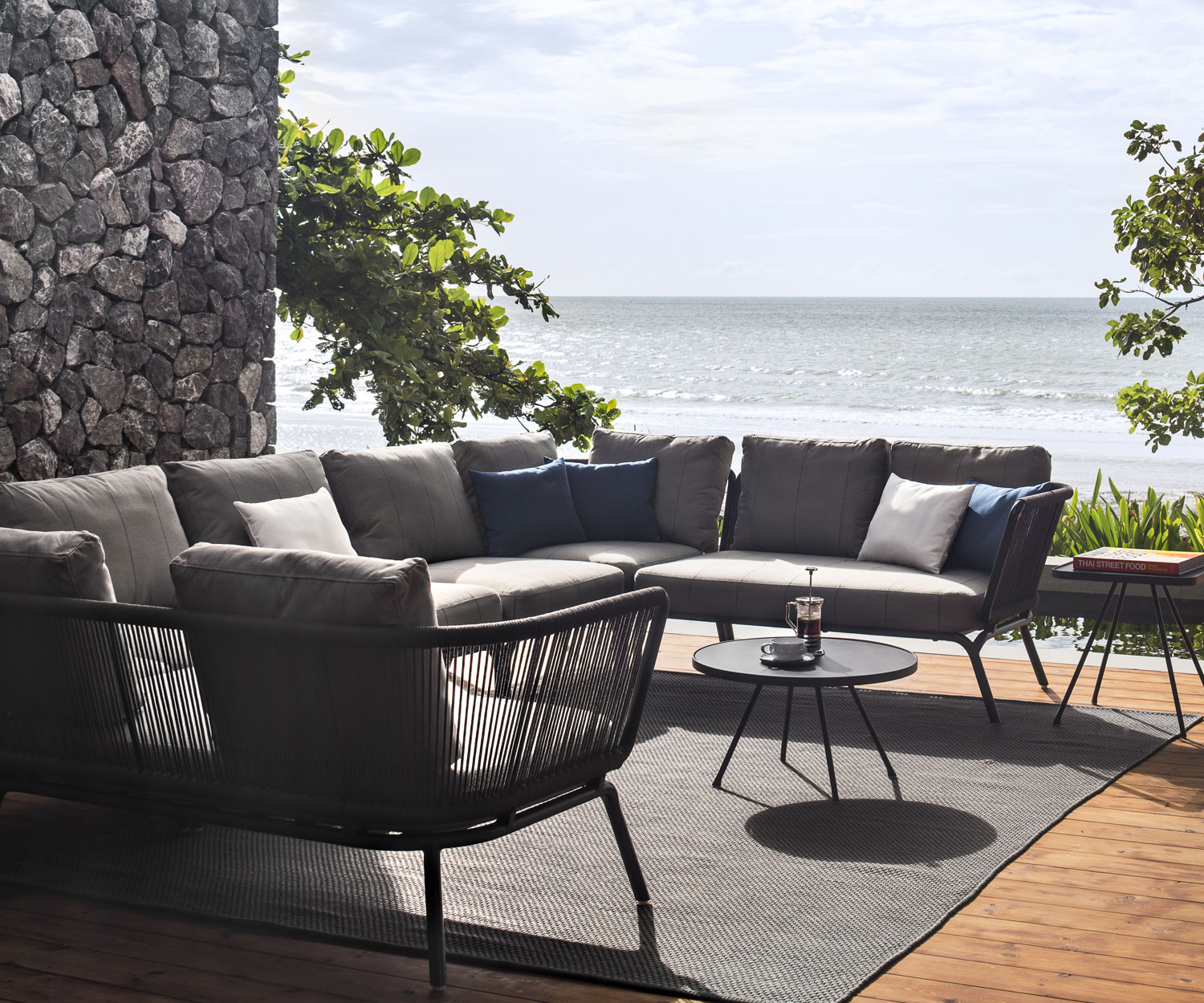 Oasiq Yland Eckbank Design Sofa mit Polsterauflage in Grau auf einer Terrasse