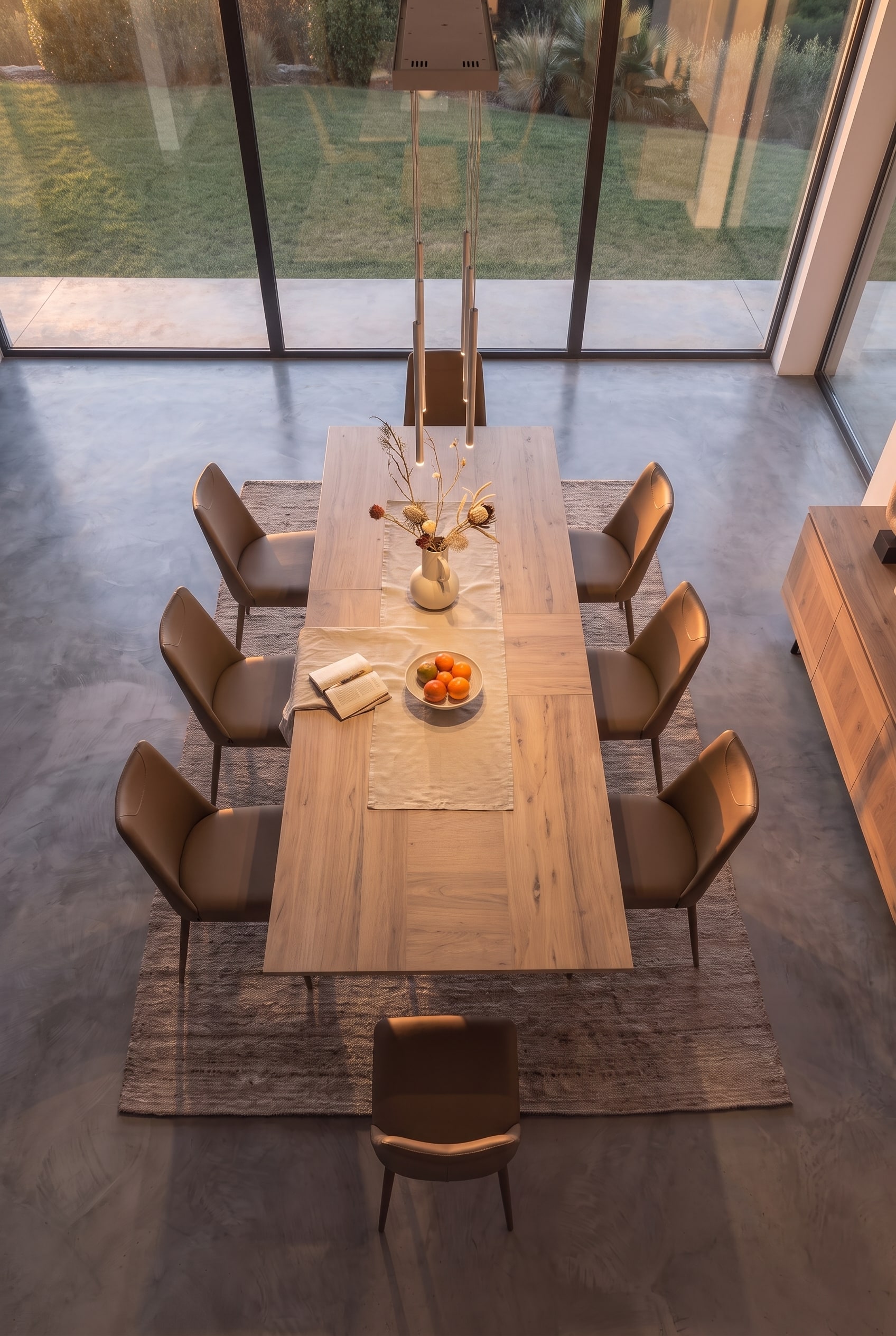 Vue plongeante sur une table à manger entièrement déployée avec huit chaises sur un tapis clair.