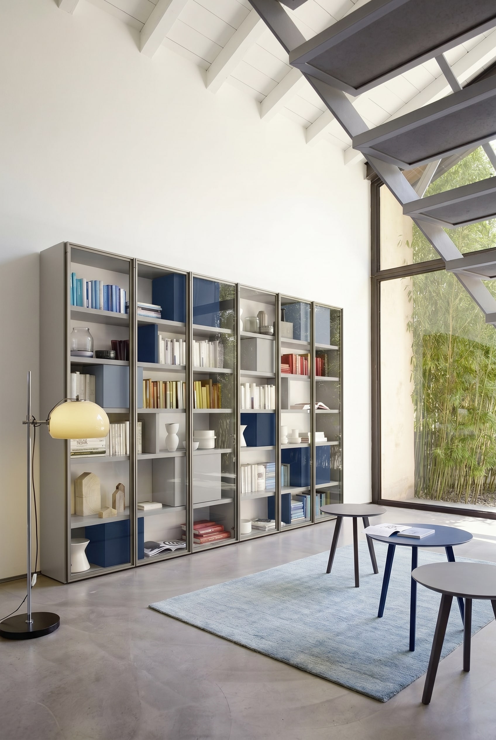 Lichtgraues ma&szlig;gefertigtes B&uuml;cherregal mit minimalen Fachabst&auml;nden und integrierten blauen Boxen