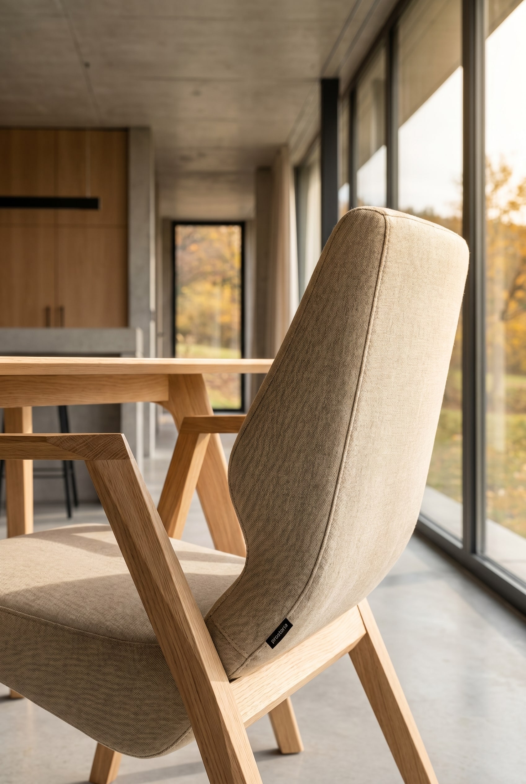 Salle &agrave; manger &eacute;l&eacute;gante avec un fauteuil Prostoria Oblique avec structure en bois en bout de table devant des fen&ecirc;tres pleine hauteur