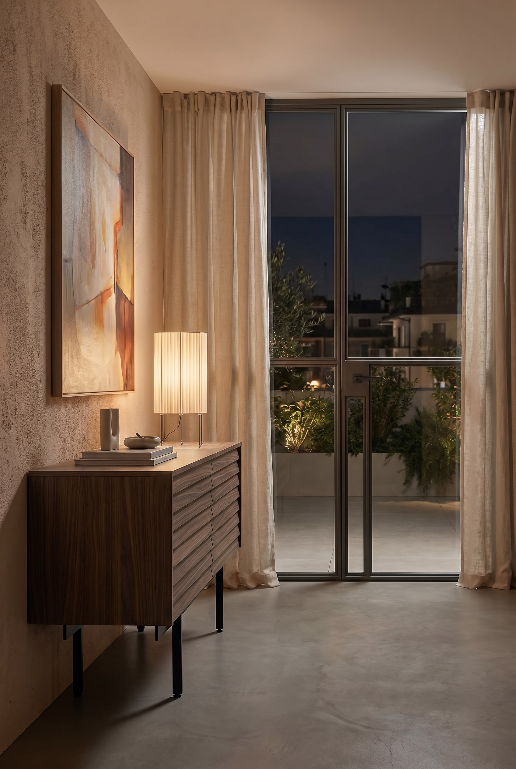 Chambre confortable avec un buffet bas en bois et une lampe de table avec un abat-jour en tissu pliss&eacute; beige sous une lumi&egrave;re chaude