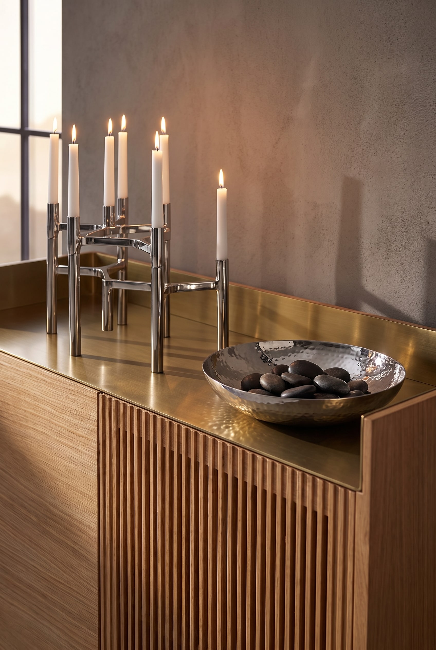 Sideboard aus hellem Eichenholz mit Lamellenfront und einer Aluminium-Deckplatte, bestückt mit kühlen, silbernen Kerzenständern und einer Edelstahlschale