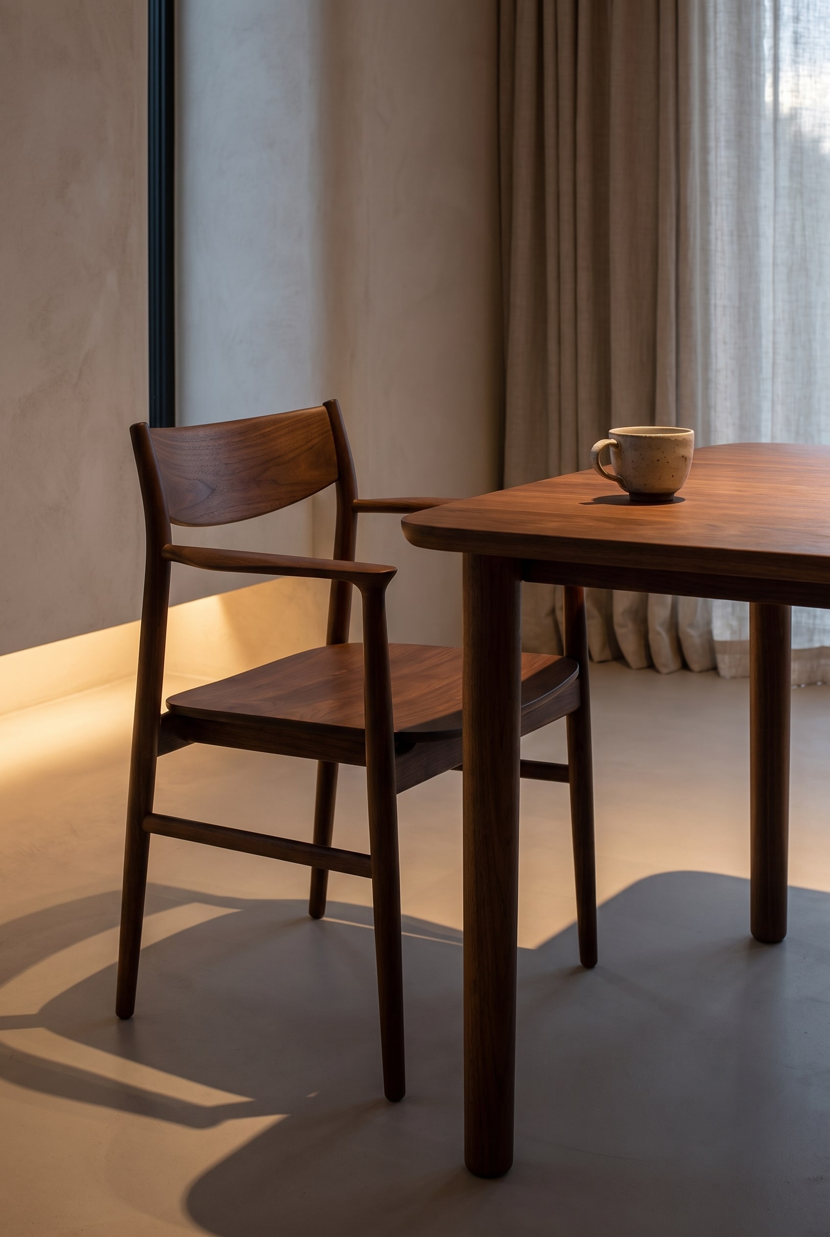 Detailaufnahme eines dunkelbraunen Holzstuhls mit flacher Silhouette und haptischer Sitzfläche am Esstisch