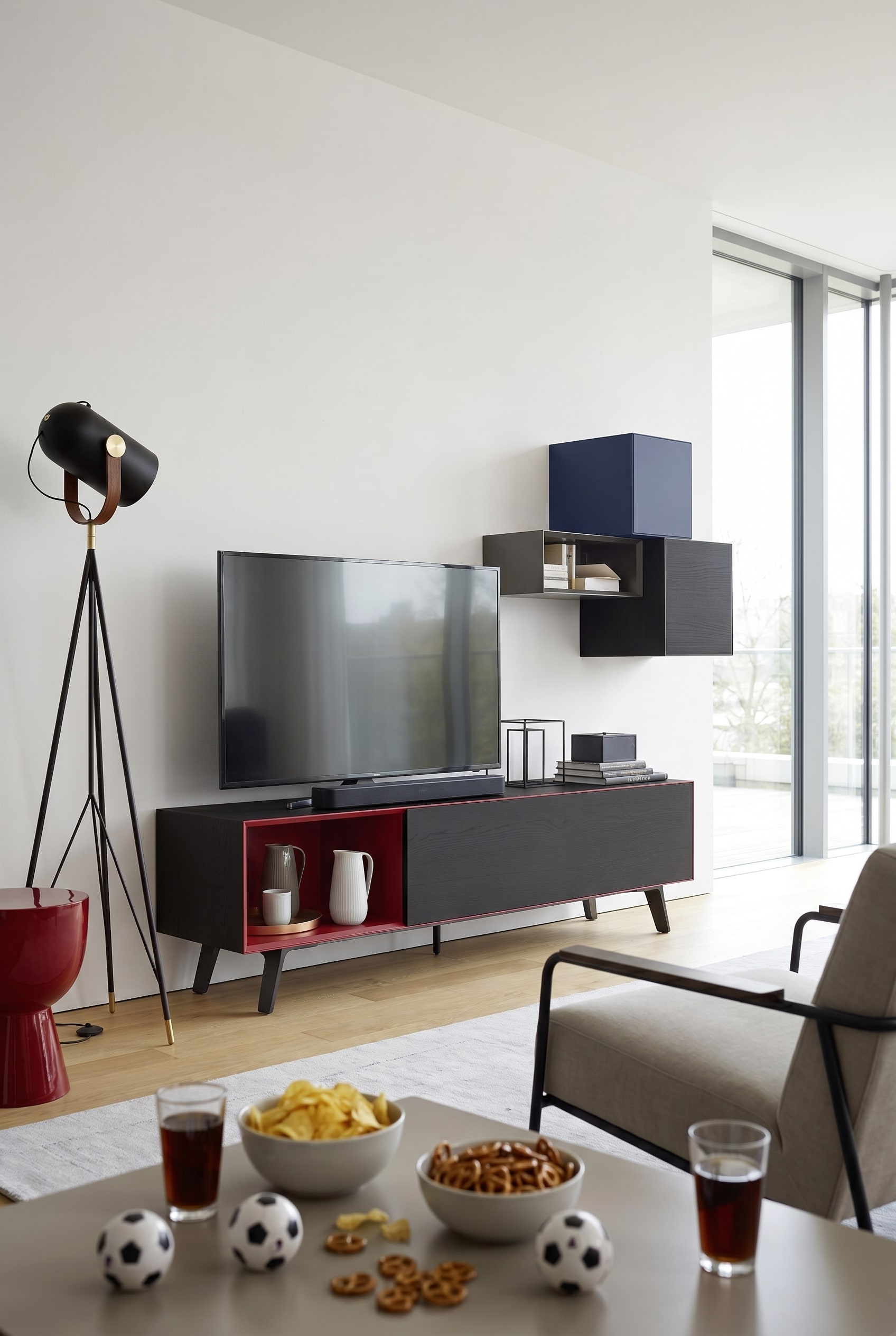 Reduziertes Wohnzimmer mit mattwei&szlig;em Lowboard, einem gro&szlig;en Fernseher und einer kompakten Soundbar davor