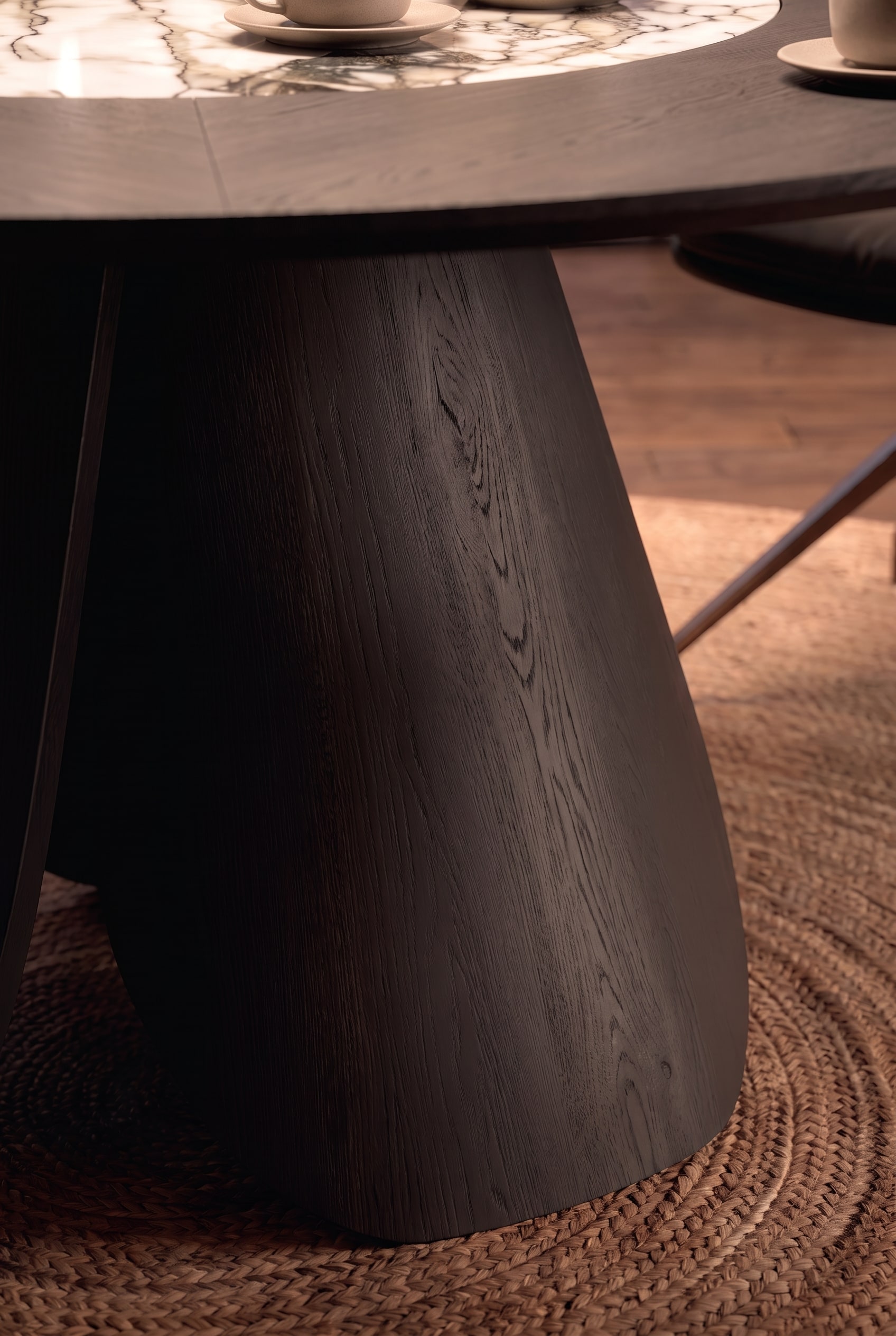 Gros plan du pied de table massif, incurvé vers l'intérieur, en bois teinté foncé avec veinure visible.